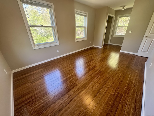 spare room featuring baseboards and dark wood finished floors