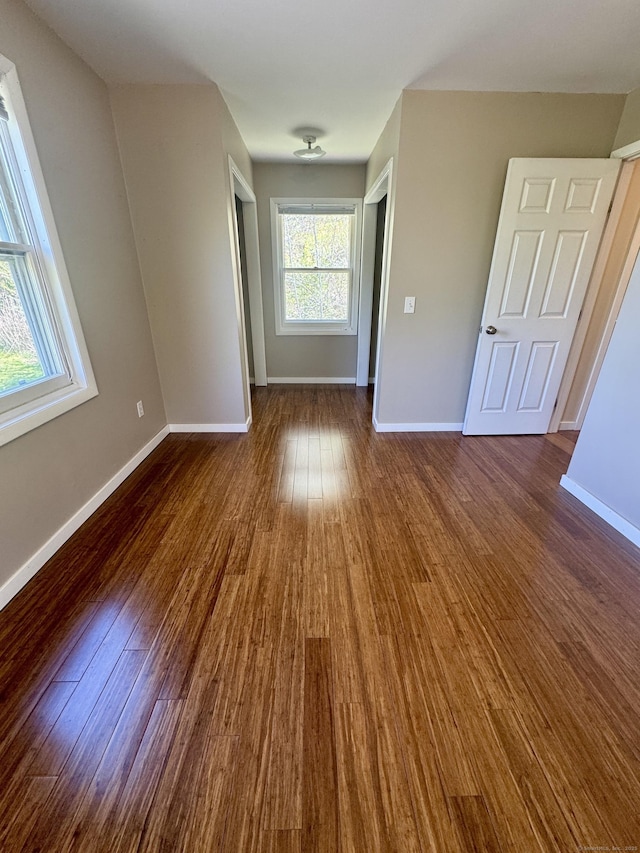 spare room featuring baseboards and dark wood-type flooring