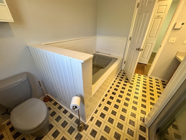bathroom with a garden tub and toilet