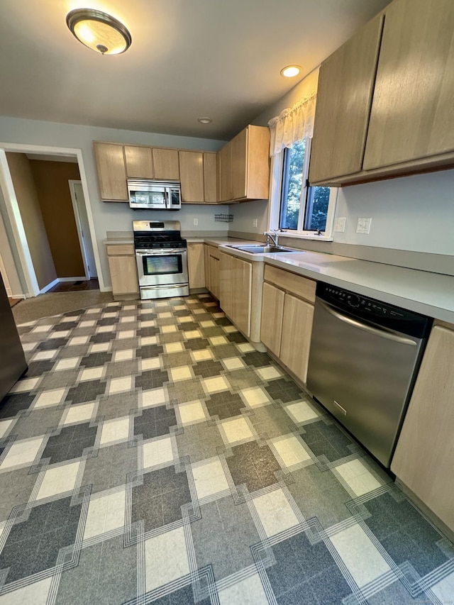 kitchen with light countertops, appliances with stainless steel finishes, light brown cabinets, and a sink