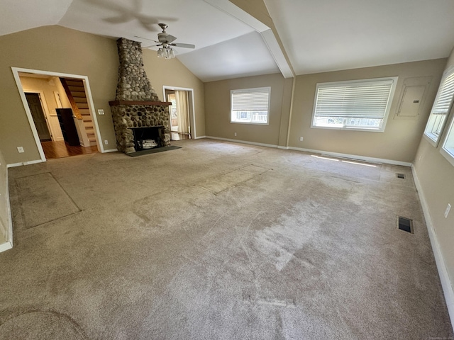 unfurnished living room with a healthy amount of sunlight, a ceiling fan, a stone fireplace, and lofted ceiling