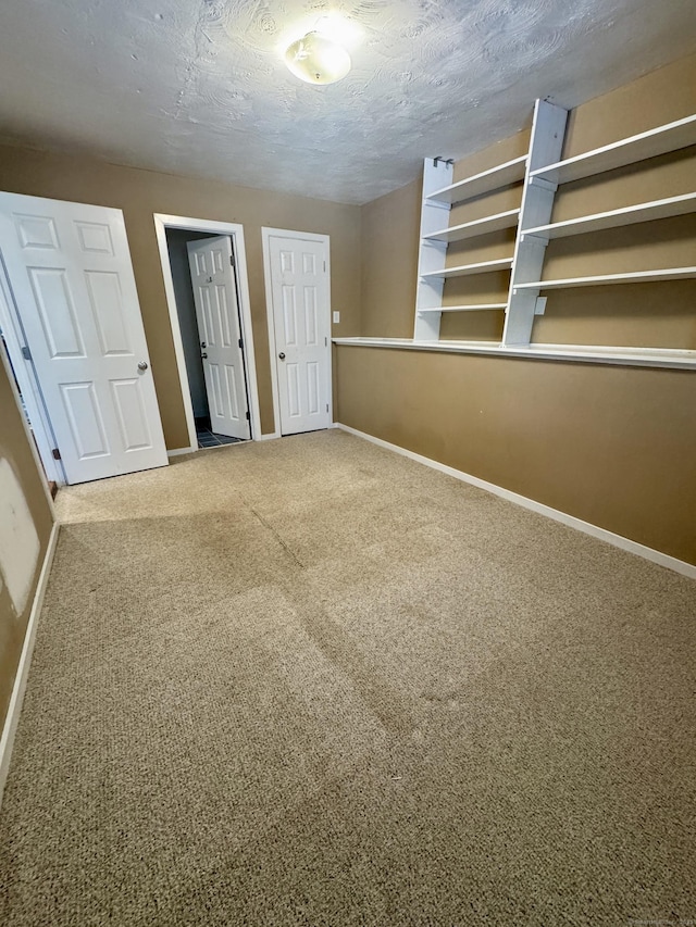 unfurnished bedroom featuring carpet floors, a textured ceiling, and baseboards