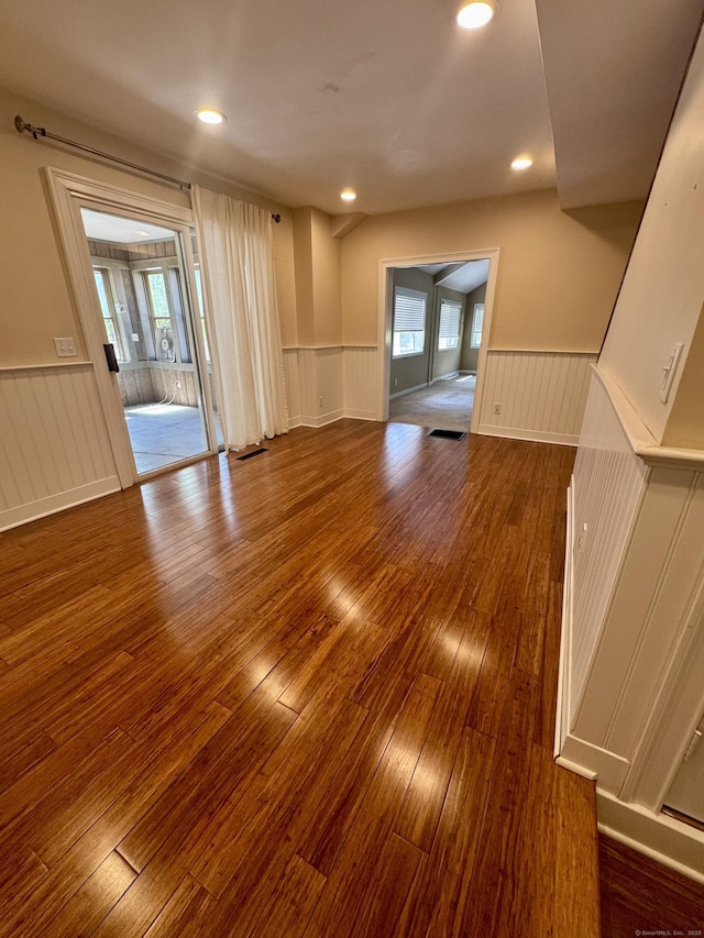 spare room featuring wood-type flooring, wainscoting, a wealth of natural light, and a decorative wall