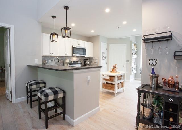 41 Stratton Forest Way, Simsbury, CT 06070 - kitchen featuring appliances with stainless steel finishes, dark countertops, light wood-type flooring, backsplash, and white cabinetry