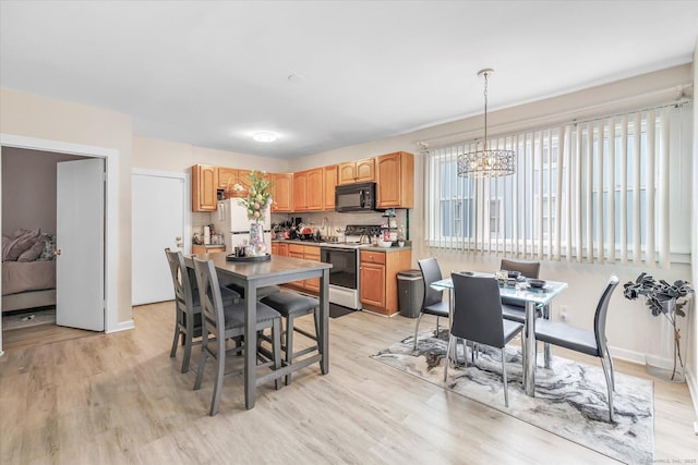 kitchen with light wood-style flooring, a notable chandelier, white appliances, and hanging light fixtures