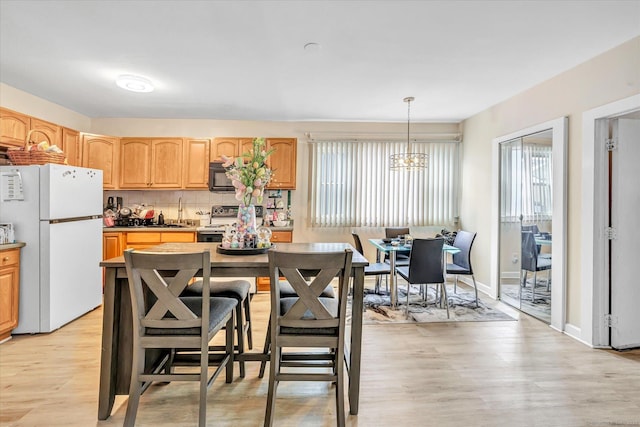 kitchen featuring black microwave, light brown cabinetry, electric range oven, freestanding refrigerator, and a wealth of natural light