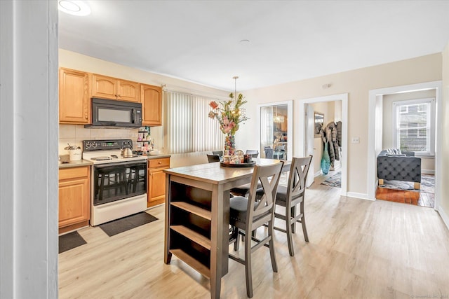 kitchen with electric range, black microwave, light brown cabinets, light wood-style floors, and light countertops