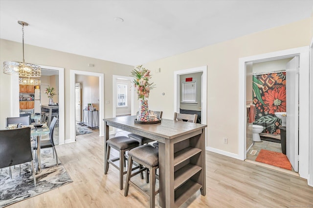 dining space featuring baseboards, light wood-type flooring, and a chandelier