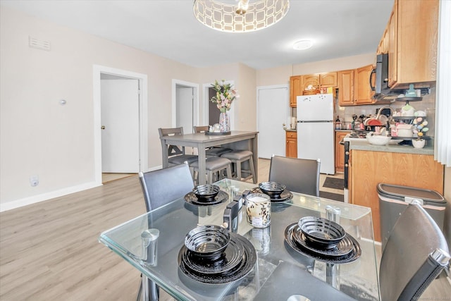 dining space featuring baseboards, light wood-style flooring, and visible vents