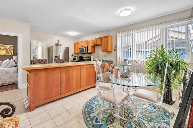 kitchen featuring light countertops, stainless steel appliances, light tile patterned floors, and a wealth of natural light