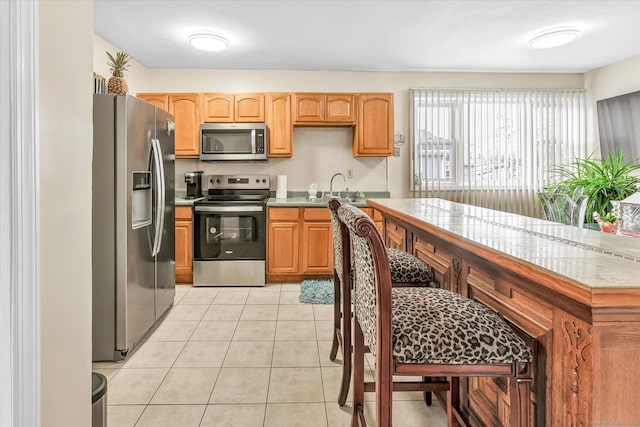 kitchen featuring light tile patterned floors, appliances with stainless steel finishes, a sink, and light countertops