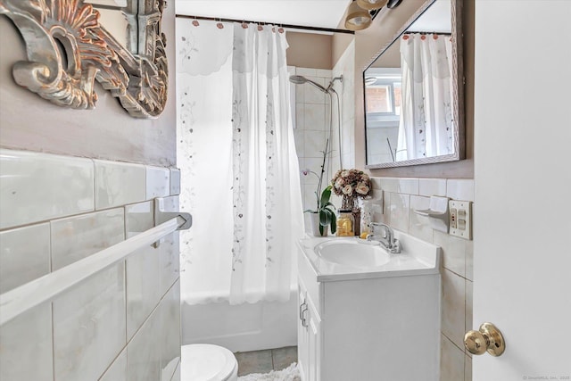 bathroom with vanity, toilet, tile patterned floors, shower / bathtub combination with curtain, and tile walls