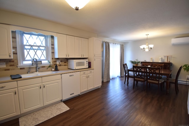 kitchen featuring white appliances, a sink, a wall mounted AC, dark wood-style floors, and a notable chandelier