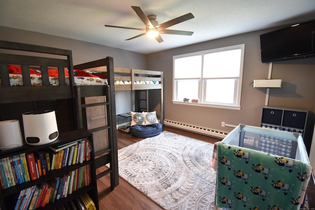 bedroom featuring a ceiling fan, baseboards, wood finished floors, and a baseboard radiator