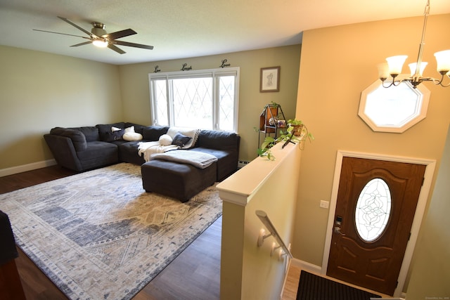living area featuring wood finished floors, baseboards, and ceiling fan with notable chandelier