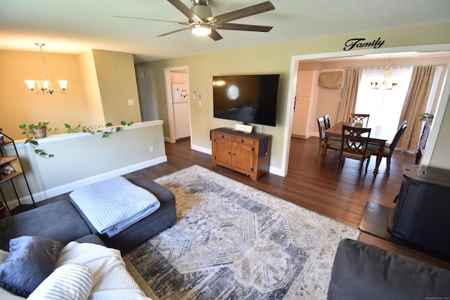 living area with dark wood-style flooring, ceiling fan with notable chandelier, and baseboards