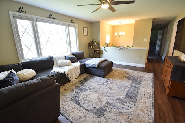 living area with dark wood-type flooring, baseboards, and ceiling fan with notable chandelier