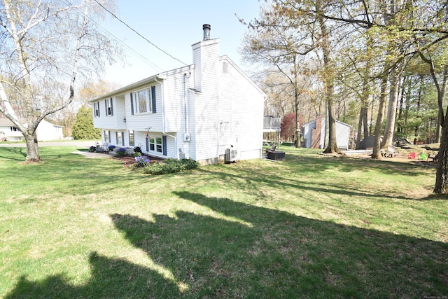 exterior space featuring cooling unit, a lawn, and a chimney