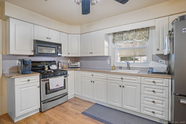 330 Flagler Ave, Stratford, CT 06614 - kitchen with appliances with stainless steel finishes, a sink, light wood-type flooring, and white cabinets