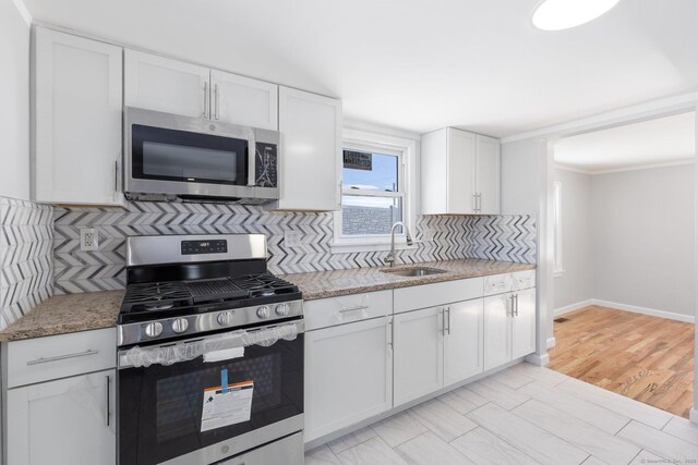 kitchen featuring tasteful backsplash, stainless steel appliances, white cabinets, and a sink