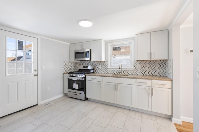 kitchen featuring decorative backsplash, a sink, visible vents, stainless steel appliances, and baseboards