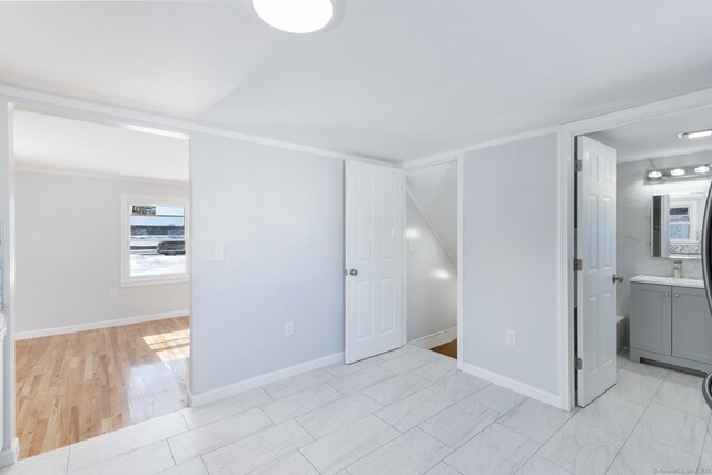 unfurnished bedroom featuring a sink, connected bathroom, and baseboards