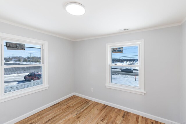 unfurnished room with ornamental molding, visible vents, light wood finished floors, and baseboards