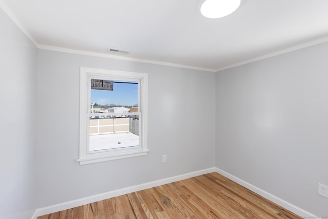spare room with baseboards, visible vents, light wood-type flooring, and crown molding