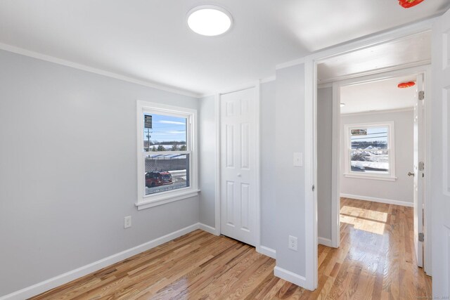 unfurnished bedroom featuring a closet, multiple windows, and light wood-style floors