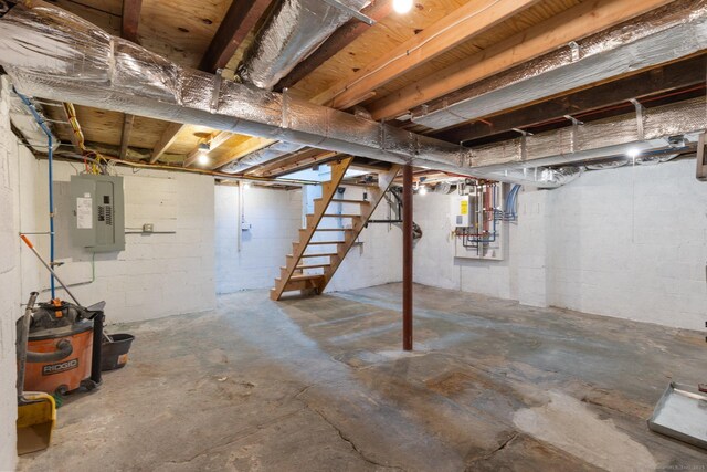 unfinished below grade area featuring stairway, concrete block wall, and electric panel