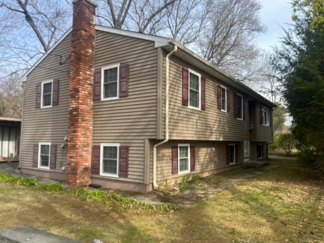 view of home's exterior with a chimney and a lawn