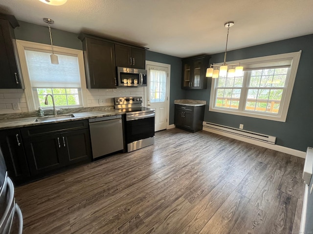 kitchen with dark wood finished floors, stainless steel appliances, baseboard heating, and a sink