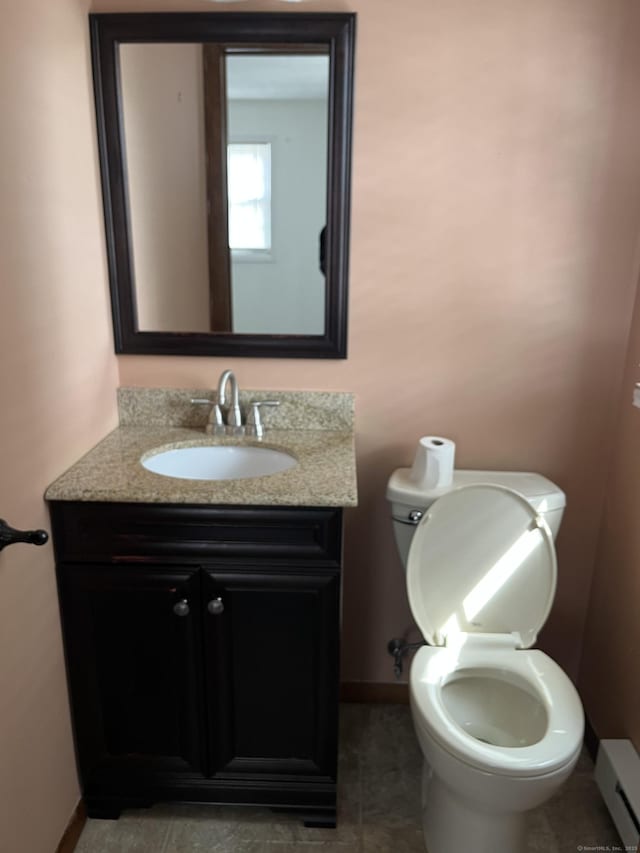 half bath featuring toilet, baseboard heating, vanity, and baseboards