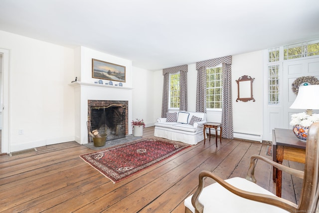 living room featuring a fireplace with flush hearth, a baseboard heating unit, a wealth of natural light, and hardwood / wood-style flooring
