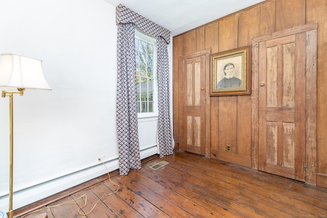 foyer entrance featuring visible vents, dark wood-type flooring, and wooden walls