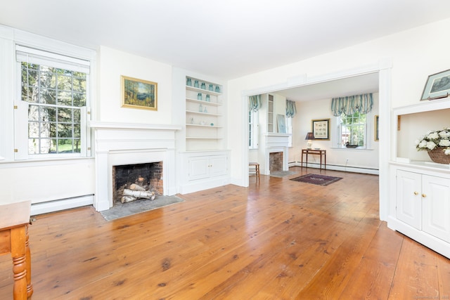 living area featuring a fireplace with flush hearth, a baseboard radiator, a baseboard heating unit, and hardwood / wood-style flooring