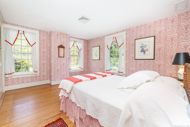 bedroom featuring wallpapered walls, visible vents, and light wood finished floors