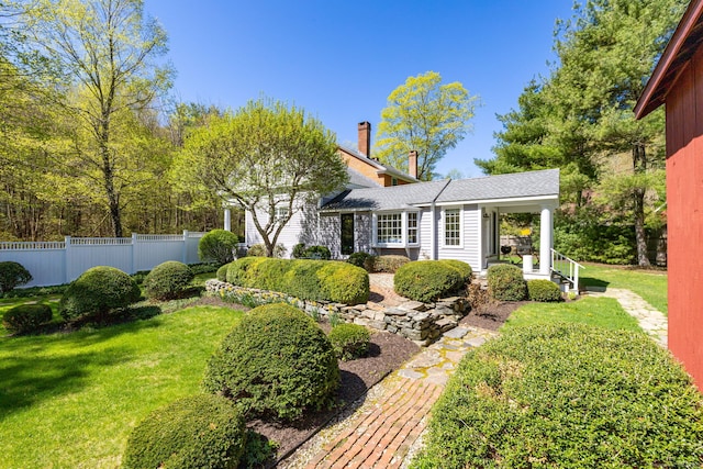 view of front of home featuring fence, a chimney, and a front lawn