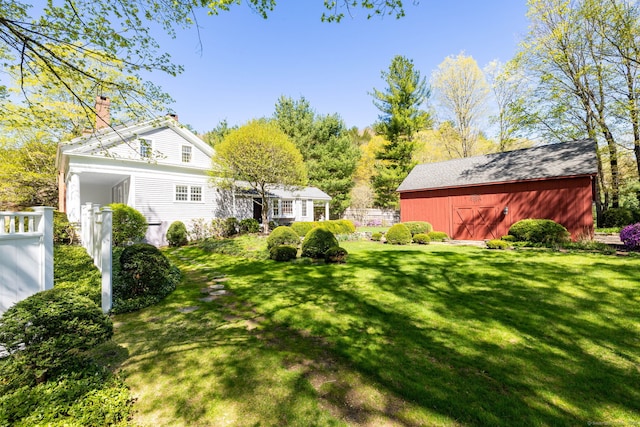 view of yard with a barn, fence, and an outdoor structure