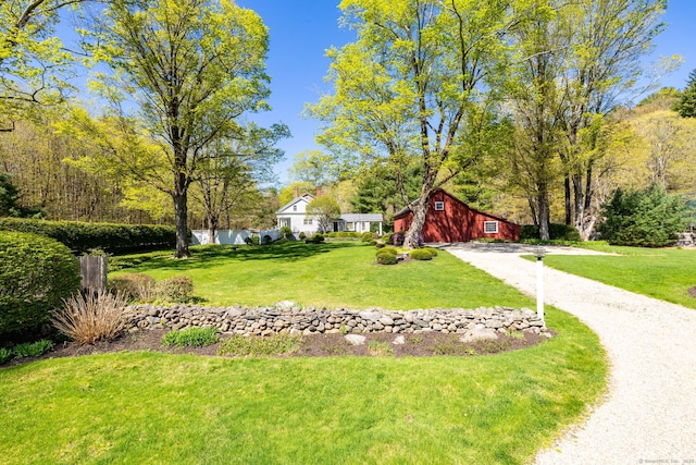 exterior space featuring a lawn, dirt driveway, and a barn