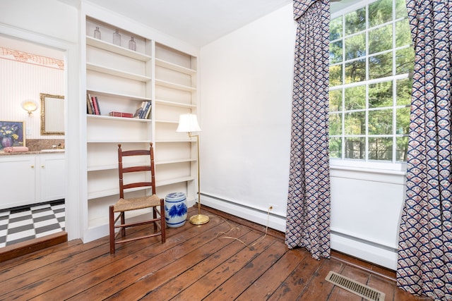 unfurnished room featuring visible vents, a sink, a baseboard heating unit, and a wealth of natural light
