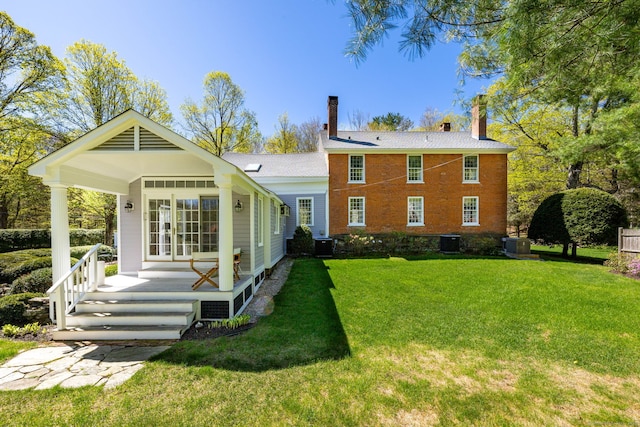 rear view of house with a yard, a chimney, and central AC unit