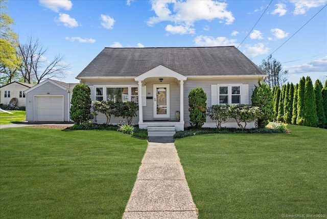 cape cod-style house featuring roof with shingles, a front yard, and a detached garage