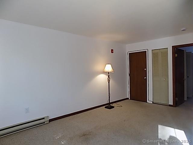 carpeted spare room with baseboards and a baseboard heating unit