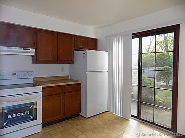 kitchen featuring white appliances, light tile patterned flooring, and exhaust hood