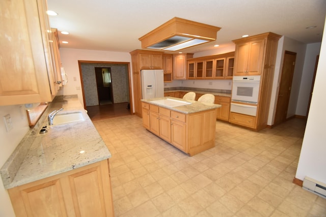 kitchen featuring a sink, white appliances, a center island, light floors, and a warming drawer