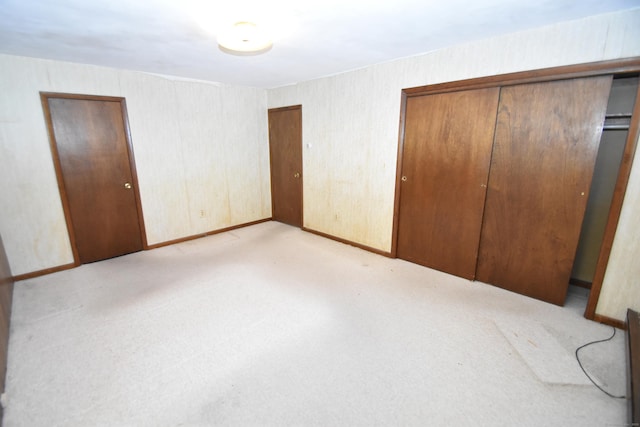 unfurnished bedroom with baseboards, a closet, and light colored carpet