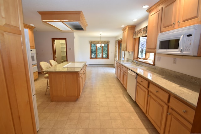 kitchen with light stone countertops, a notable chandelier, white appliances, a center island, and recessed lighting