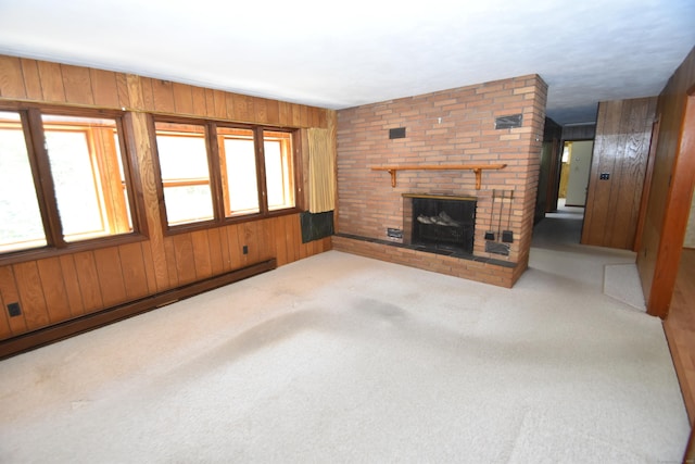 unfurnished living room featuring carpet, a brick fireplace, a baseboard heating unit, and wooden walls