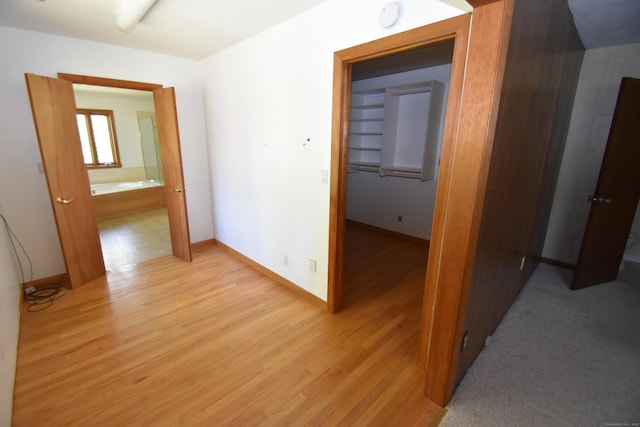corridor with light wood-style floors and baseboards